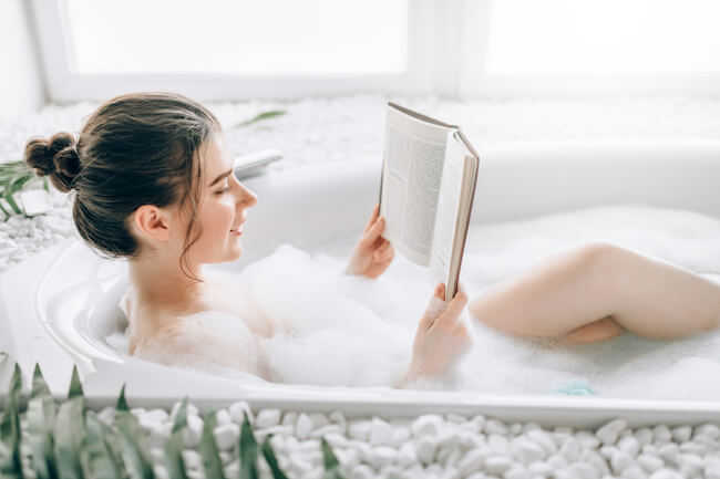 湯船に浸かって全身浴しながら本を読む女性