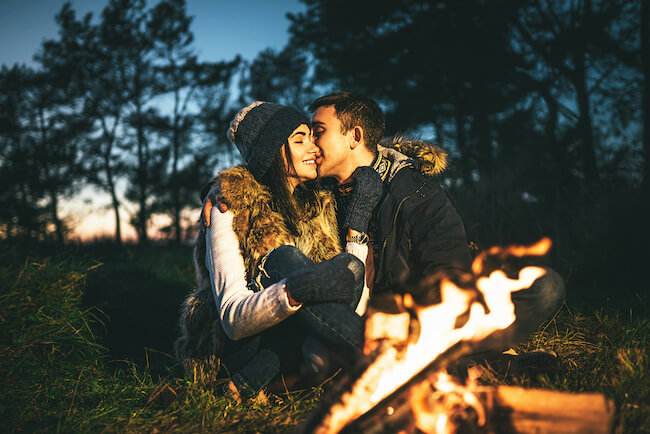 焚き火の前でキスする男女