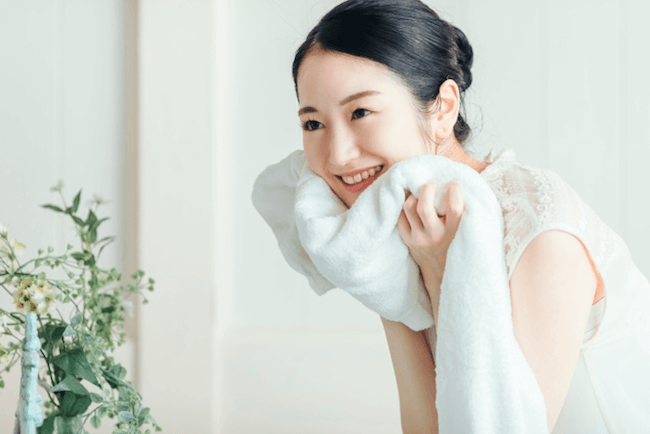 洗顔後タオルで顔を抑える女性